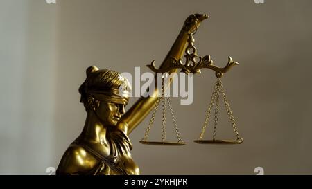 Primo piano di una statua dorata di Lady Justice che regge le scale dell'equilibrio, simboleggiando equità e imparzialità. I dettagli intricati riflettono la princi Foto Stock