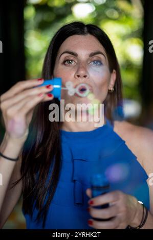 Ritratto interno di un'attraente donna caucasica sulla trentina che soffia bolle di sapone e si diverte Foto Stock