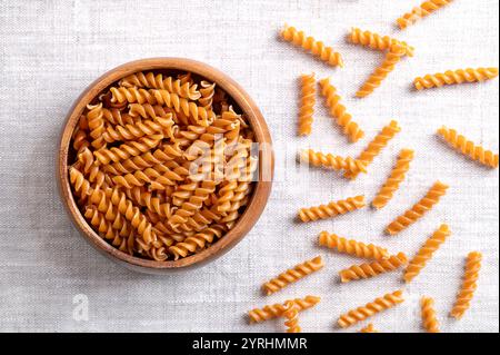 Pasta a spirale di ceci, spaghetti senza glutine in un recipiente di legno su tessuto di lino. Piccoli fusilli, una varietà di pasta a forma elicoidale o cavatappi. Foto Stock