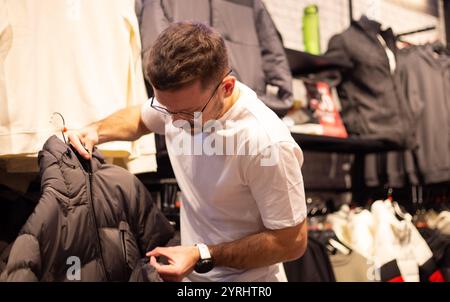 Un uomo guarda scarpe e vestiti in un negozio Foto Stock