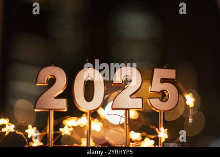 Bellissime candele dorate festive da 2025 di notte con luci bokeh e stelle. Felice anno nuovo 2025 Foto Stock