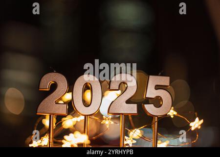 Bellissime candele dorate festive da 2025 di notte con luci bokeh e stelle. Felice anno nuovo 2025 Foto Stock