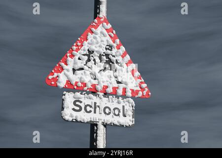 Segnaletica stradale triangolare coperta da neve durante la tempesta. Illustrazione in 3D del concetto di chiusura delle scuole a causa di un segnale di ghiaccio e di condizioni meteorologiche avverse Foto Stock