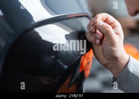 L'uomo professionista rimuove graffi e vernici sopra di esso in garage. Dettagli Foto Stock