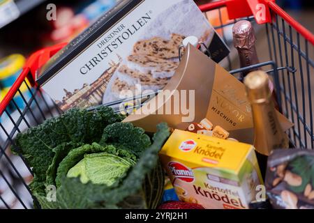 Colonia, Germania. 4 dicembre 2024. Un carrello completo con anatra polacca, verdure, frutta, stollen natalizi, gnocchi, vino frizzante, vino, cioccolatini e cioccolato Santas sono stati superati gli scaffali di un supermercato. (Al sondaggio dpa: "Every Second Person Saving on food shopping for Christmas") credito: Rolf Vennenbernd/dpa/Alamy Live News Foto Stock