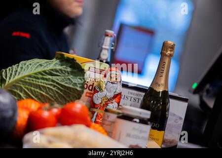Colonia, Germania. 4 dicembre 2024. Vari articoli di un viaggio di shopping natalizio si trovano su un nastro trasportatore al momento del check-out di un supermercato. (Al sondaggio dpa: "Ogni secondo utente risparmia denaro quando compra cibo per Natale") credito: Rolf Vennenbernd/dpa/Alamy Live News Foto Stock