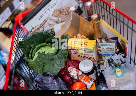 Colonia, Germania. 4 dicembre 2024. Un carrello completo con anatra polacca, verdure, frutta, stollen natalizi, gnocchi, vino frizzante, vino, cioccolatini e cioccolato Santas sono stati superati gli scaffali di un supermercato. (Al sondaggio dpa: "Every Second Person Saving on food shopping for Christmas") credito: Rolf Vennenbernd/dpa/Alamy Live News Foto Stock