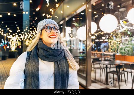 giovane donna che gode di luci festive in inverno sera Foto Stock