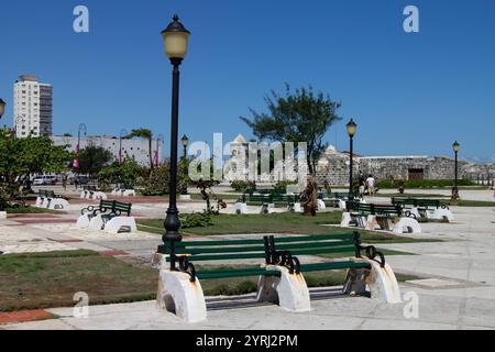 Un piacevole parco con panche in legno e la fortezza del Castillo de San Salvador de la Punta XVI secolo nel centro di la Habana, l'Avana, Cuba Foto Stock