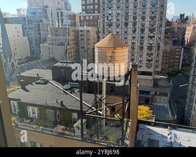 Tipico serbatoio d'acqua di New York sopraelevato sul tetto dell'edificio che serve. Foto Stock