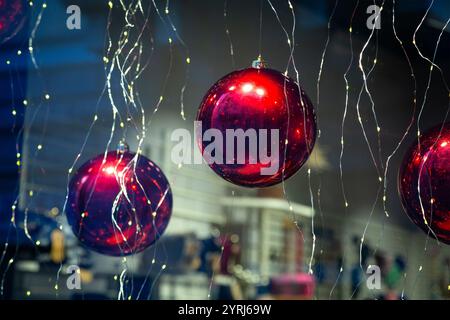 Un gruppo di palline di Natale di colore rosso brillante è elegantemente appeso al soffitto Foto Stock