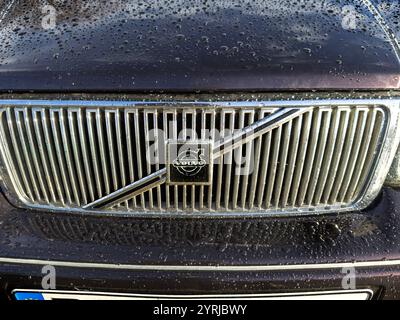 Primo piano di una classica griglia per auto Volvo V90 vintage con gocce di pioggia e l'iconico logo circolare con finitura metallizzata Foto Stock