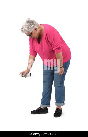 vista laterale di una donna anziana accovacciata che dipinge con spray su sfondo bianco Foto Stock