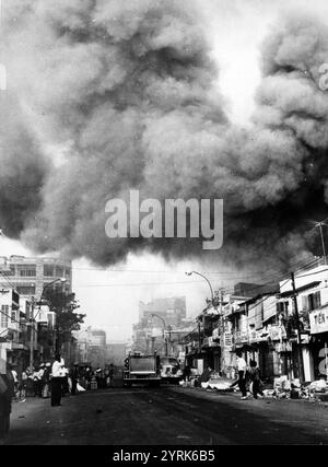 Il fumo nero copre le aree della capitale e i camion dei pompieri si precipitano sulle scene degli incendi incendiati durante gli attacchi dei Viet Cong durante il periodo festivo delle vacanze Tet. Saigon, 1968 anni Foto Stock