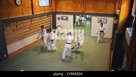 Arti marziali, dimostrazioni di lotta e persone con apprendimento, esercizio fisico e karate nel dojo. Giappone, centro di allenamento e fitness con sport, disciplina e. Foto Stock