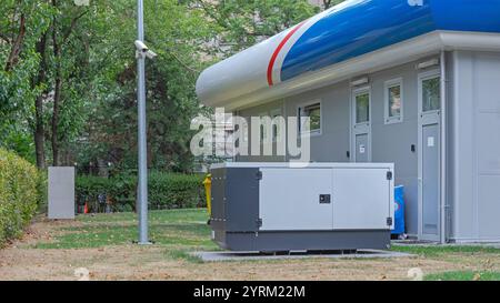 Generatore di energia di backup dietro l'edificio industriale elettricità ausiliaria di emergenza Foto Stock