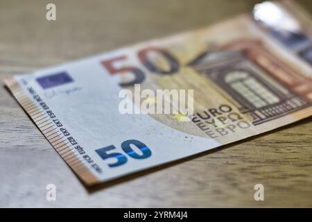 Una banconota da 50 euro poggia su una superficie di legno marrone chiaro. L'immagine è in primo piano, concentrandosi sui dettagli della fattura, tra cui il numero "50" e l'arco Foto Stock