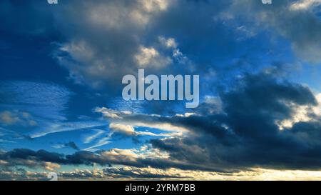 Un colpo largo di un cielo per lo più nuvoloso. Il cielo mostra una miscela di nuvole scure, grigio-blu e nuvole di cullo più chiare, bianche e grigie. Macchie di blu Foto Stock