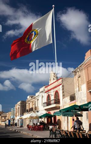 Malta, a sud-est, Marsaxlokk, waterfront edifici e bandiera Foto Stock