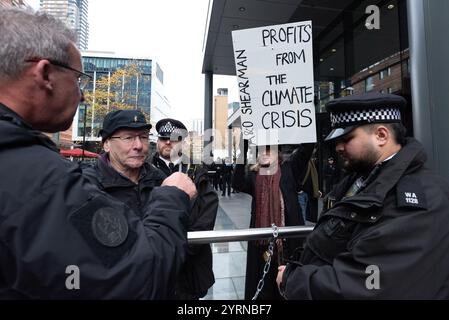 Londra, Regno Unito. 4 dicembre 2024. Gli agenti di polizia parlano con un uomo (seconda sinistra) incatenato alle ringhiere mentre gli attivisti per il clima dall'estinzione la ribellione protesta contro l'ufficio londinese dello studio legale globale A&o Shearman, invitando l'azienda a "tagliare i legami" con le compagnie di combustibili fossili che rappresenta. Crediti: Ron Fassbender/Alamy Live News Foto Stock