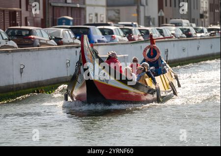 Aveiro, Portogallo - 11 settembre 2024: Colorata barca tradizionale che naviga in acque calme con i passeggeri che si godono una giornata di sole Foto Stock