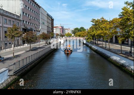 Aveiro, Portogallo - 11 settembre 2024: Serena vista su un canale alberato con acqua limpida e edifici moderni in una giornata di sole Foto Stock