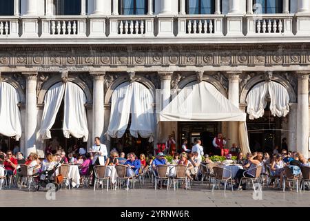 Turisti che amano il tramonto al caffè Florian, Piazza San Marco, San Marco, Venezia, Veneto, Italia. Aperto nel 1720, è il caffè più antico d'Italia. Foto Stock