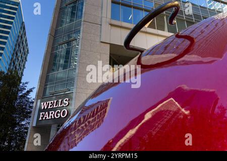 Eine Nahaufnahme einer großen roten Weihnachtskugel, deren glänzende Oberfläche die umliegenden Gebäude reflektiert. Im Hintergrund ist das markante Logo des Wells Fargo-Gebäudes a Charlotte, North Carolina, zu sehen, eingebettet in die moderne Architektur der Stadt. Die Szene kombiniert die festliche Dekoration mit der urbanen Skyline und schafft eine interessante Perspektive zwischen Kunstinstallation und Geschäftsviertel. *** Un primo piano di una grande bauble natalizia rossa, la sua superficie lucida che riflette gli edifici circostanti l'impressionante logo dell'edificio Wells Fargo a Charlotte, North C Foto Stock