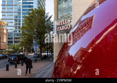Eine Nahaufnahme einer großen roten Weihnachtskugel, deren glänzende Oberfläche die umliegenden Gebäude reflektiert. Im Hintergrund ist das markante Logo des Wells Fargo-Gebäudes a Charlotte, North Carolina, zu sehen, eingebettet in die moderne Architektur der Stadt. Die Szene kombiniert die festliche Dekoration mit der urbanen Skyline und schafft eine interessante Perspektive zwischen Kunstinstallation und Geschäftsviertel. *** Un primo piano di una grande bauble natalizia rossa, la sua superficie lucida che riflette gli edifici circostanti l'impressionante logo dell'edificio Wells Fargo a Charlotte, North C Foto Stock