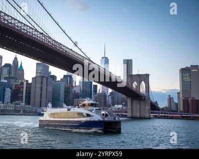 Barca che passa sotto il ponte di Brooklyn Foto Stock