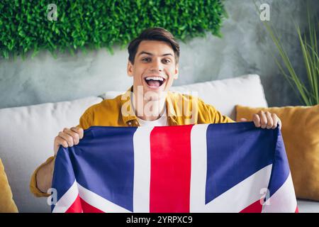 Giovane felice con bandiera britannica in un luminoso ed elegante salotto interno Foto Stock