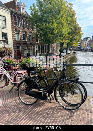 Biciclette moderne parcheggiate vicino al canale d'acqua in città Foto Stock