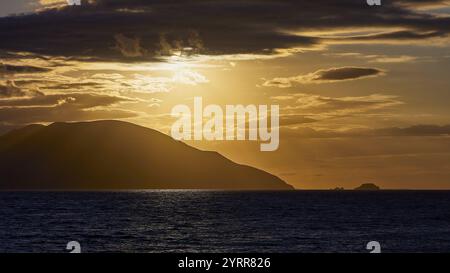 Il cielo mostra un tramonto spettacolare con nuvole scure e un'isola all'orizzonte, tramonto, Kassos, Karpathos, isole al largo, Dodecaneso, Isole greche Foto Stock