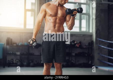 Allestitore maschile dedicato impegnato nel sollevamento di pesi in un moderno ambiente di palestra Foto Stock