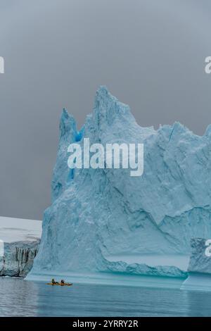 Isola di Cuverville, Penisola Antartica - 31 gennaio 2024. I turisti antartici stanno esplorando le acque vicino all'isola di Cuverville, utilizzando un kayak da mare. Foto Stock