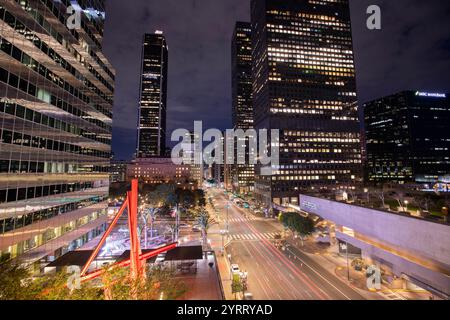 Los Angeles, California, USA - 29 novembre 2024: Il traffico serale scorre lungo Flower Street attraverso il quartiere finanziario di Downtown LOS ANGELES. Foto Stock