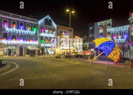 Águeda, Portogallo - 27 novembre 2024: Vista notturna del centro città: Edifici adornati con luci natalizie a forma di ombrelli. Foto Stock