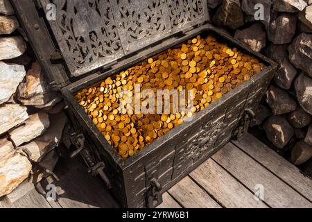 Una grande cassa piena di monete d'oro Foto Stock