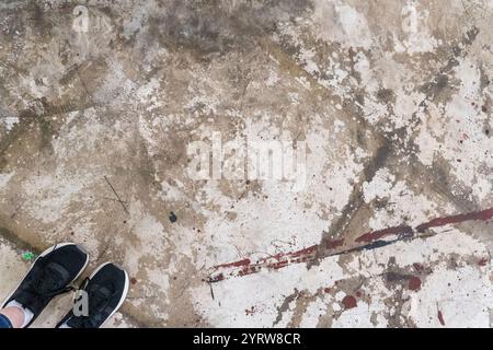 Pavimento in calcestruzzo con stampe di scarpe e macchie in un ambiente industriale durante il giorno Foto Stock