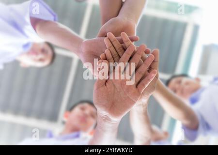 Mani diverse impilate in Unity e Teamwork. Molti bambini impilano le mani insieme. Simbolo del lavoro di squadra e della motivazione. Foto Stock