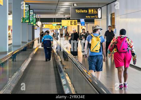 Passeggeri sul passaggio pedonale mobile nell'edificio del terminal dell'aeroporto internazionale Schipol, Amsterdam, Olanda Foto Stock