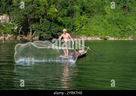Un pescatore che lancia una rete sul lago Ba Be nel Parco Nazionale Ba Be nella provincia di Bac Kan, Vietnam Foto Stock