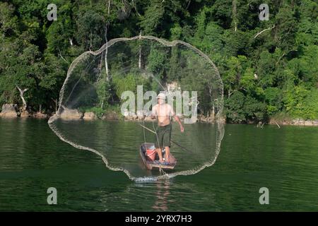 Un pescatore che lancia una rete sul lago Ba Be nel Parco Nazionale Ba Be nella provincia di Bac Kan, Vietnam Foto Stock