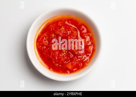 Ajika o adjika. Salsa rossa di pomodori, aglio e peperoni. Vista dall'alto su sfondo bianco. Ajika o adjika. Salsa rossa di pomodori, aglio e p Foto Stock