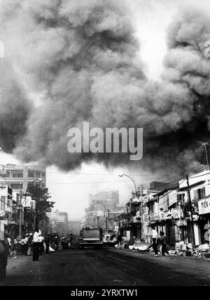 Il fumo nero copre le aree della capitale e i camion dei pompieri si precipitano sulle scene degli incendi incendiati durante gli attacchi dei Viet Cong durante il periodo festivo delle vacanze Tet. Saigon, 1968 anni Foto Stock