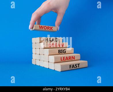 Lavora sodo sogno grande imparare veloce simbolo. Blocchi di legno con le parole lavorano sodo sogno grande imparare velocemente. Bellissimo sfondo blu. Mano d'affari. Affari Foto Stock