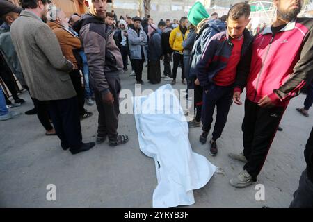 Le persone pregano accanto ai corpi dei palestinesi uccisi dopo gli scioperi israeliani, all'ospedale al-Aqsa di Deir al Balah le persone pregano accanto ai corpi dei palestinesi uccisi dopo gli scioperi israeliani, all'ospedale al-Aqsa di Deir al Balah, nella Striscia di Gaza centrale, 5 dicembre 2024. Secondo il Ministero della salute palestinese a Gaza, almeno 25 palestinesi sono stati uccisi a seguito di attacchi aerei israeliani nella Striscia di Gaza meridionale e centrale. Più di 45.000 palestinesi e più di 1.400 israeliani sono stati uccisi, secondo il Ministero della salute palestinese e l'esercito israeliano, dalla guerra israeliana nella Striscia di Gaza Foto Stock