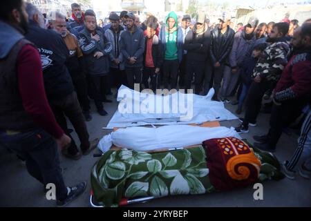 Le persone pregano accanto ai corpi dei palestinesi uccisi dopo gli scioperi israeliani, all'ospedale al-Aqsa di Deir al Balah le persone pregano accanto ai corpi dei palestinesi uccisi dopo gli scioperi israeliani, all'ospedale al-Aqsa di Deir al Balah, nella Striscia di Gaza centrale, 5 dicembre 2024. Secondo il Ministero della salute palestinese a Gaza, almeno 25 palestinesi sono stati uccisi a seguito di attacchi aerei israeliani nella Striscia di Gaza meridionale e centrale. Più di 45.000 palestinesi e più di 1.400 israeliani sono stati uccisi, secondo il Ministero della salute palestinese e l'esercito israeliano, dalla guerra israeliana nella Striscia di Gaza Foto Stock