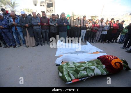 Le persone pregano accanto ai corpi dei palestinesi uccisi dopo gli scioperi israeliani, all'ospedale al-Aqsa di Deir al Balah le persone pregano accanto ai corpi dei palestinesi uccisi dopo gli scioperi israeliani, all'ospedale al-Aqsa di Deir al Balah, nella Striscia di Gaza centrale, 5 dicembre 2024. Secondo il Ministero della salute palestinese a Gaza, almeno 25 palestinesi sono stati uccisi a seguito di attacchi aerei israeliani nella Striscia di Gaza meridionale e centrale. Più di 45.000 palestinesi e più di 1.400 israeliani sono stati uccisi, secondo il Ministero della salute palestinese e l'esercito israeliano, dalla guerra israeliana nella Striscia di Gaza Foto Stock