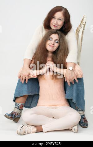 Ritratto di una madre anziana e di una figlia adulta su sfondo grigio. Suocera e nuora. Foto Stock